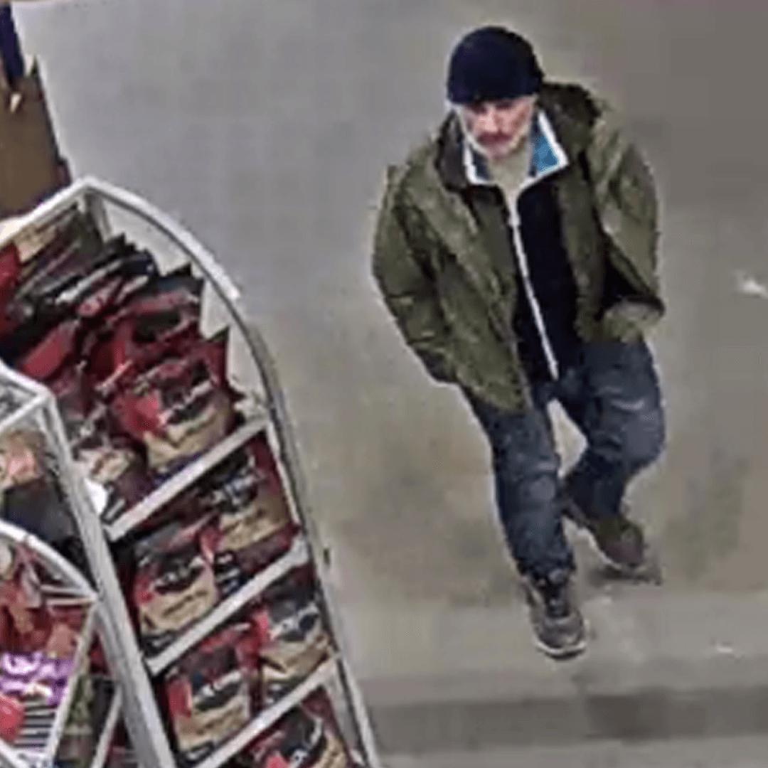 Store camera view showing a dark beanie and green jacket